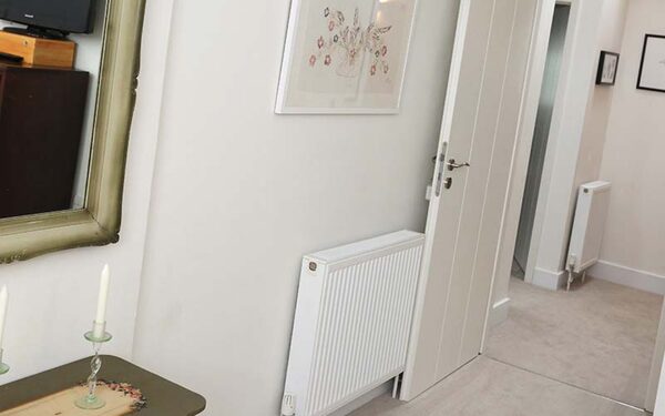 A white panel radiator installed on the wall of a home hallway