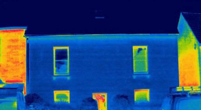 Thermal imaging photograph of a two-storey house showing heat loss through windows and walls