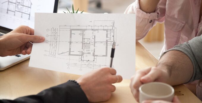 People at a desk reviewing a printed architectural floor plan together