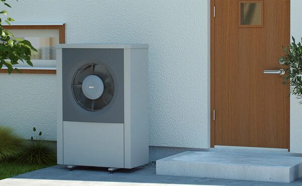 An IVT air source heat pump unit installed outside a house wall next to a wooden front door