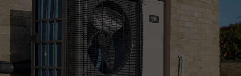 An Ideal Logic Air air source heat pump unit installed against the exterior brick wall of a house