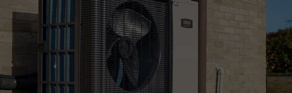 An Ideal Logic Air air source heat pump unit installed against the exterior brick wall of a house
