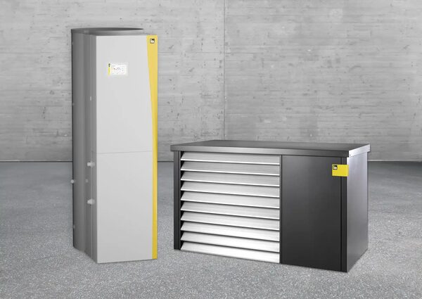 An iDM heat pump indoor unit with hot water tank beside an outdoor air-source heat pump unit against a concrete wall