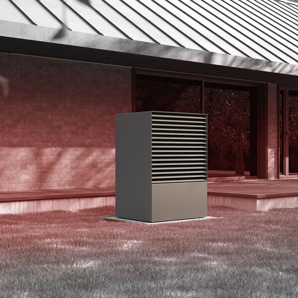 A Kronoterm ADAPT 2 air source heat pump outdoor unit installed on a lawn outside a modern house