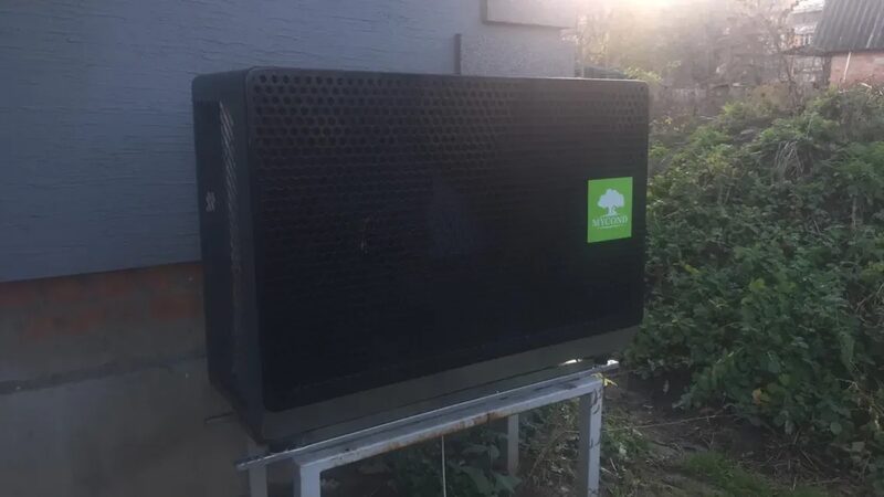 A Mycond heat pump outdoor unit installed on a metal stand against the exterior wall of a house