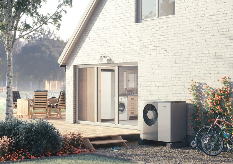 A NIBE air source heat pump unit installed outside a white brick house beside a patio and bicycles
