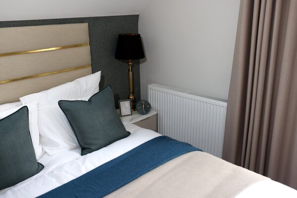 A white panel radiator installed on the wall beside a bed in a styled bedroom