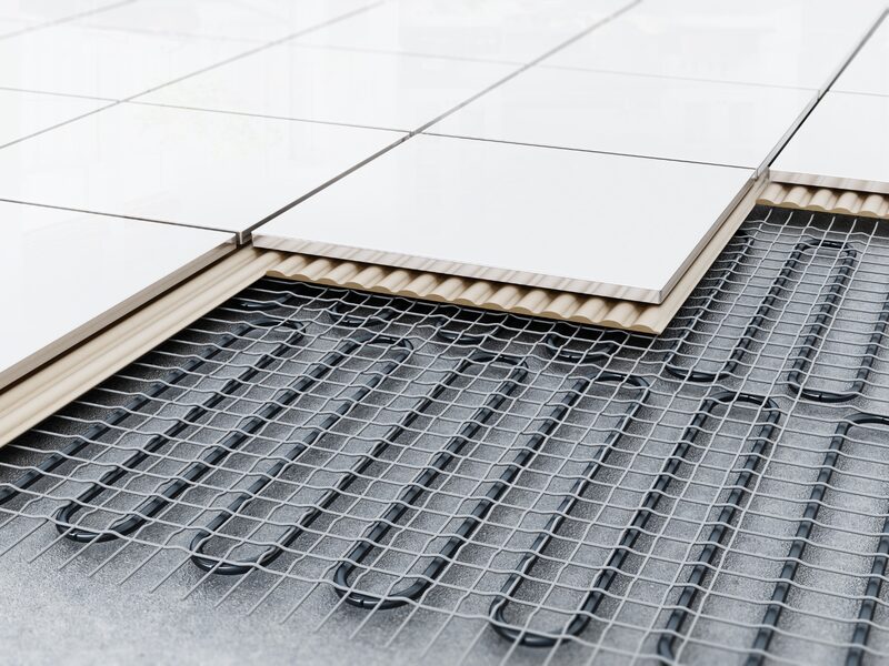 A cutaway view of an underfloor heating system with black heating pipes on mesh beneath insulation and white floor tiles