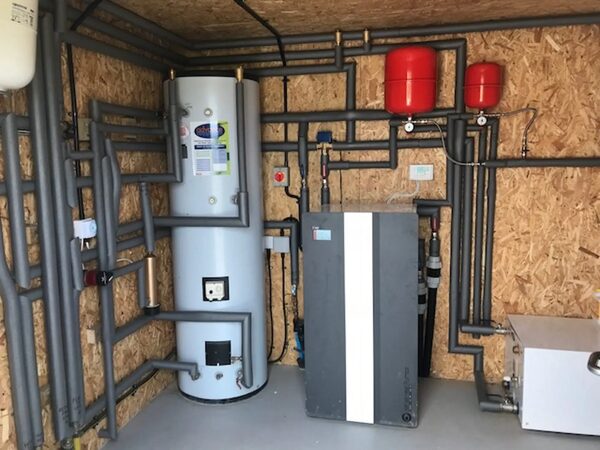 A ground source heat pump installation with a hot water cylinder, expansion vessels and pipework in a plant room