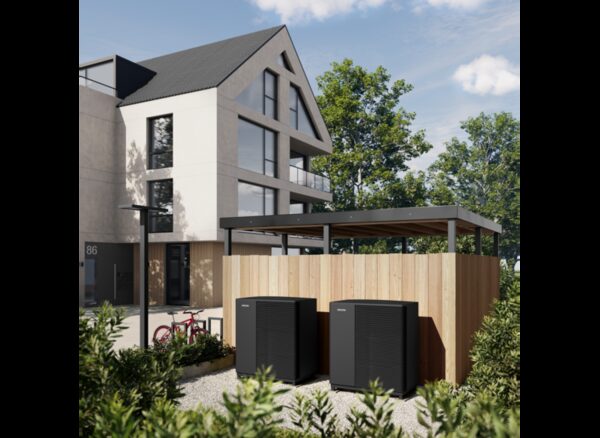 Two Stiebel Eltron air source heat pump units installed outside a modern apartment building beside a timber enclosure