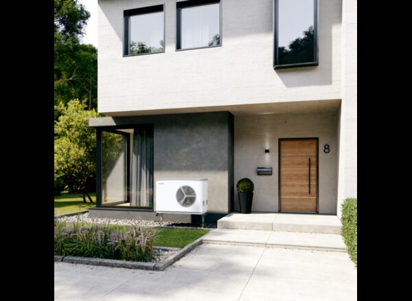 A Stiebel Eltron air source heat pump unit installed on the exterior wall of a modern house beside the front door