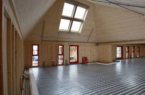 Underfloor heating pipework being installed across the floor of a timber-framed room under construction