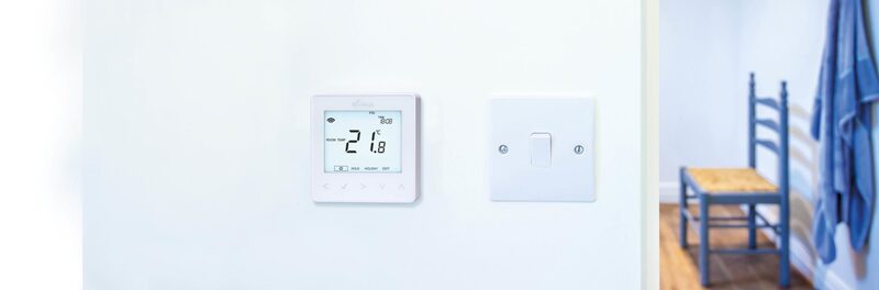 A white Nu-Heat underfloor heating thermostat on a wall showing 21.8 degrees, next to a light switch