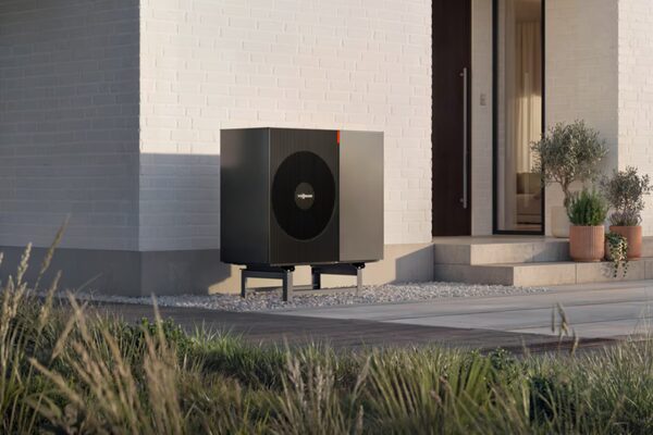 A dark grey Viessmann air source heat pump unit installed outside a modern white brick house beside the front door