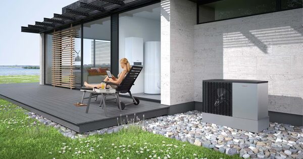 A Viessmann Vitocal 200-A monobloc air source heat pump unit installed outside a modern house terrace with a woman relaxing on a lounger