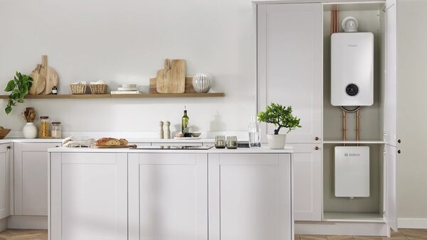 A Worcester Bosch hybrid heating system installed in a kitchen cupboard, with a wall-hung boiler unit above a hot water cylinder