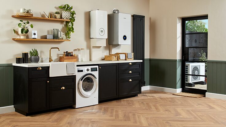 A utility room with a wall-mounted Worcester Bosch heat pump boiler and cylinder, a washing machine, and an air source heat pump unit visible outside the door