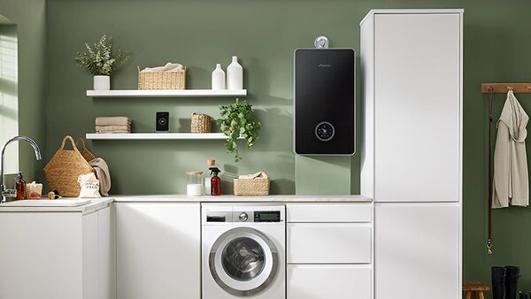 A black wall-mounted Worcester Bosch combi boiler installed in a green utility room above a washing machine
