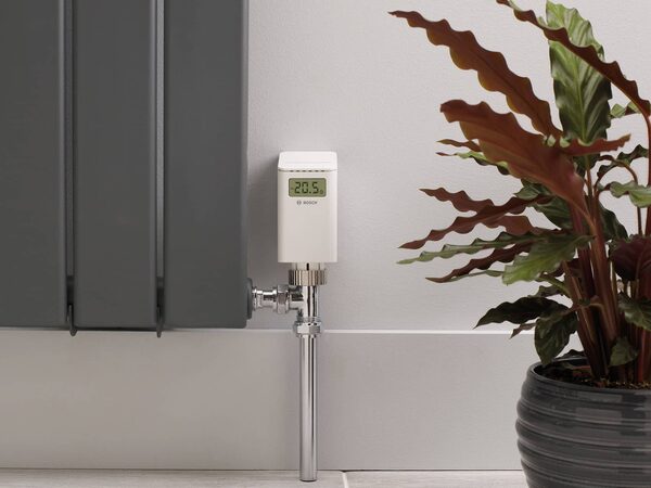 A Bosch smart thermostatic radiator valve fitted to a grey radiator next to a potted plant