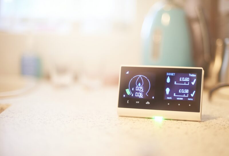 A smart meter in-home display showing energy usage and budget figures sitting on a kitchen worktop