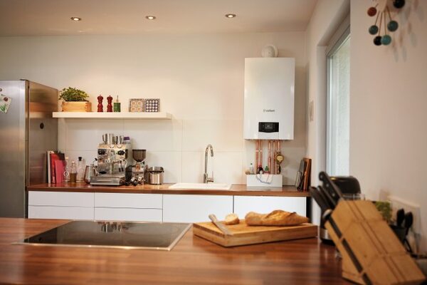 A white Vaillant wall-mounted boiler installed in a modern kitchen with copper pipework below it