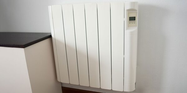 A white electric storage heater with a digital control panel mounted on a wall next to a worktop