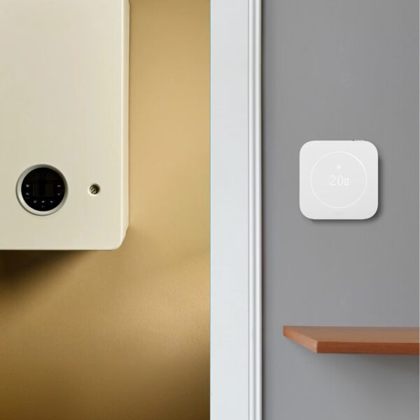 A white tado smart thermostat on a grey wall next to a wall-mounted boiler