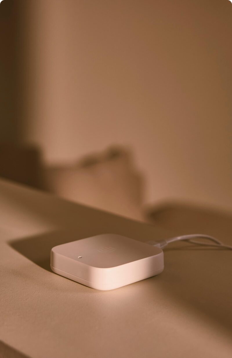 A white Hive smart hub plugged in on a table in warm lighting