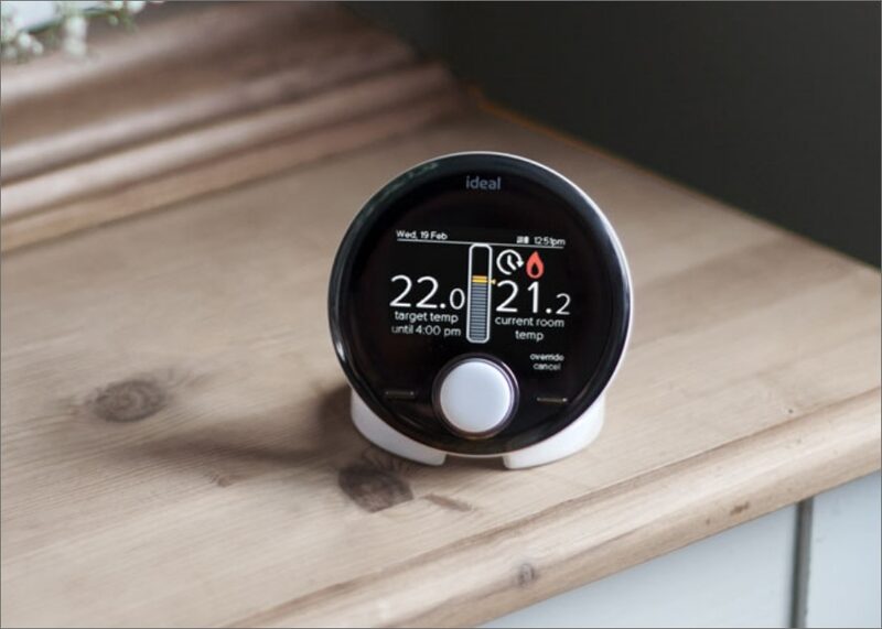 An Ideal Halo wireless boiler thermostat on a wooden mantelpiece displaying target and current room temperatures