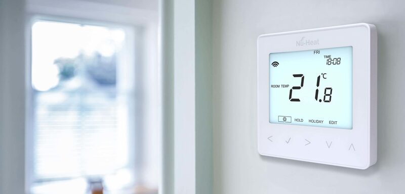 A white Nu-Heat wall-mounted digital thermostat showing a room temperature of 21.8°C