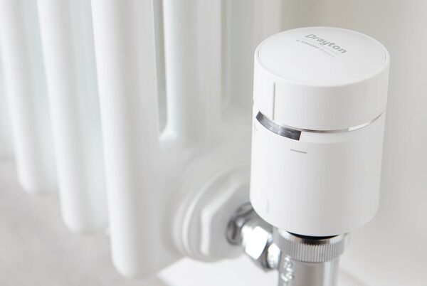 A white Drayton Wiser smart radiator thermostat fitted on a radiator valve