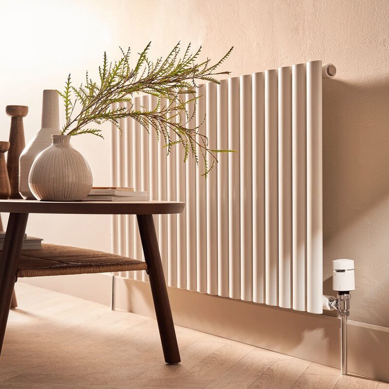 A white column radiator in a styled living room fitted with a smart thermostatic radiator valve on the pipe