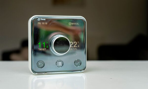 A Hive Active Heating smart thermostat with a central dial showing target and actual temperatures, sitting on a white surface