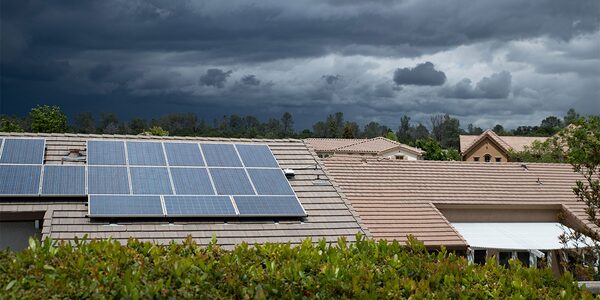 Solar panels installed on the tiled roof of a suburban house under a dark stormy sky