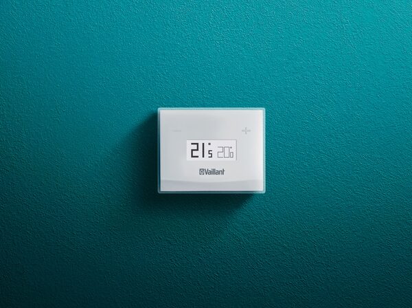 A white Vaillant vSMART smart thermostat mounted on a teal wall showing 21.5 degrees
