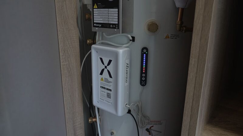 A Mixergy smart hot water cylinder installed in a cupboard, with its control unit and indicator display visible