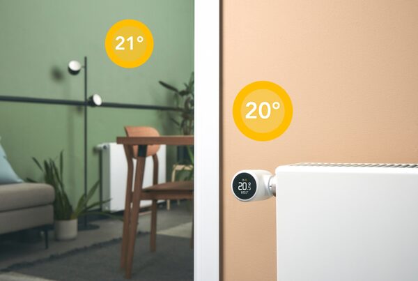 A tado° smart radiator thermostat on a white radiator showing 20°C, with a second room in the background at 21°C