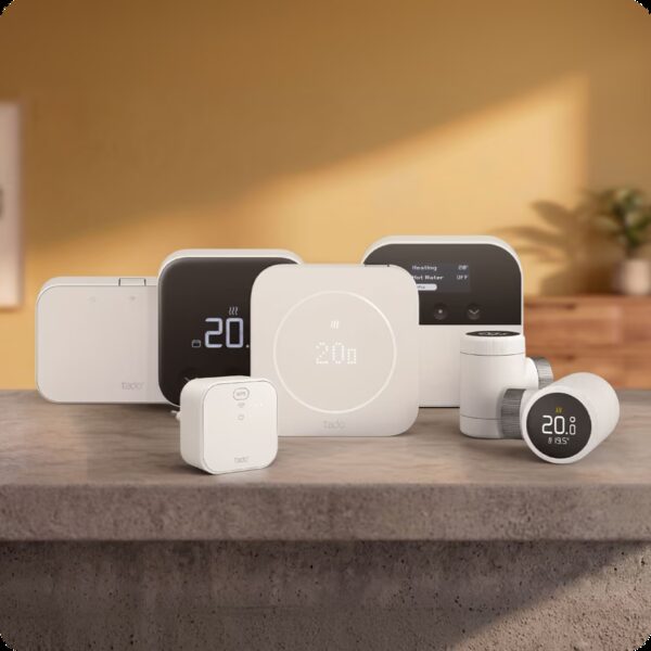 A range of tado smart heating products including thermostats, a bridge and radiator valves arranged on a stone surface