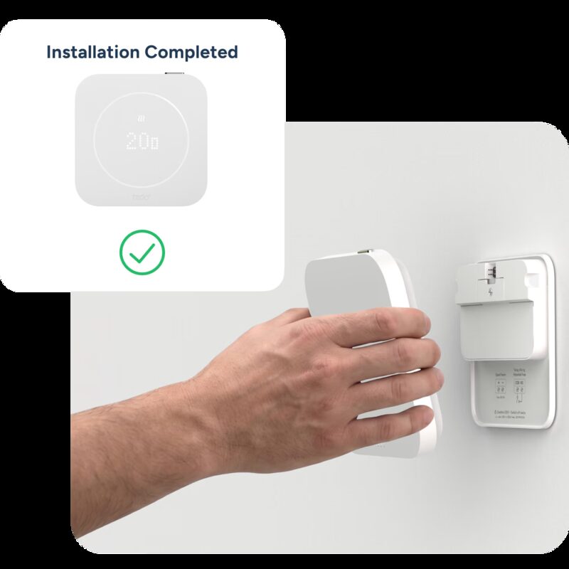 A hand mounting a white tado smart thermostat onto its wall bracket, with an 'Installation Completed' graphic showing the device display