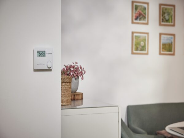 A Vaillant sensoROOM pure wall thermostat showing 20.5 degrees mounted in a living room
