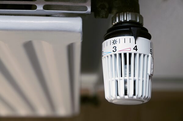 A close-up of a white thermostatic radiator valve with numbered dial fitted to a radiator