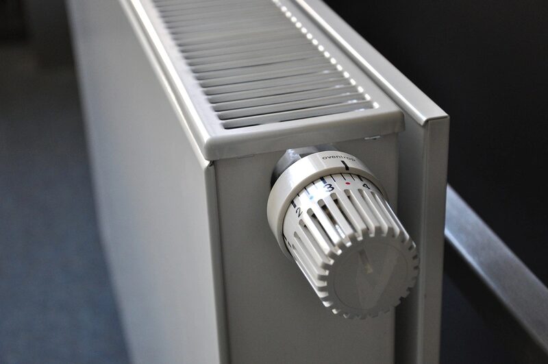 A close-up of a white panel radiator with a thermostatic radiator valve dial