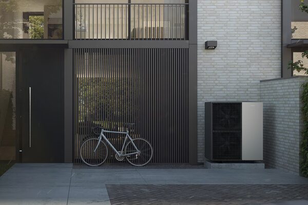 A Viessmann air source heat pump unit installed outside a modern house, with a bicycle parked nearby