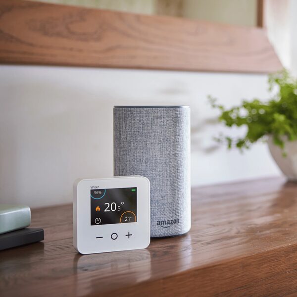A Wiser smart room thermostat showing 20.5°C next to an Amazon Echo smart speaker on a wooden shelf