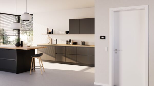 A small wall-mounted control module on the wall of a modern open-plan kitchen