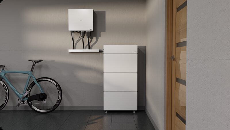 A white SolarEdge home battery unit and wall-mounted inverter installed in a garage next to a bicycle