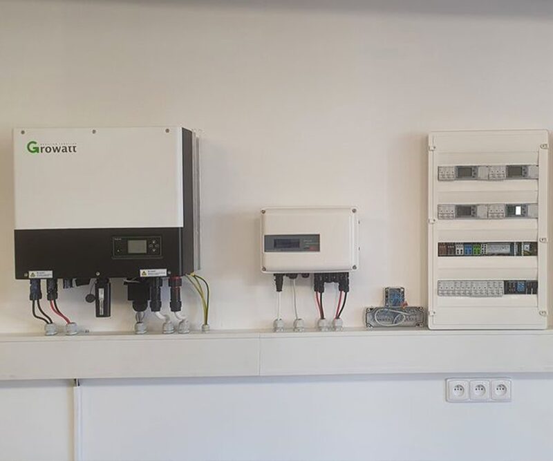 A Growatt wall-mounted battery inverter and storage system installed next to a consumer unit on an indoor wall