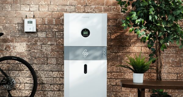 A myenergi libbi home battery unit installed against a brick wall with a small wall-mounted controller beside it