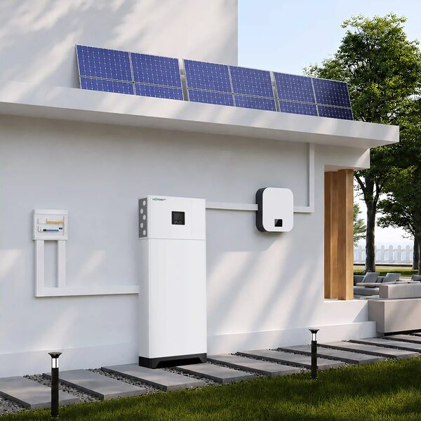 A LuxPowerTek all-in-one home battery storage unit mounted on an exterior wall beside a consumer unit, with a wall-mounted inverter and rooftop solar panels on a modern white house