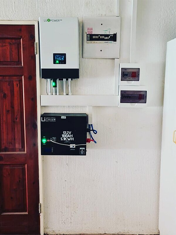 A LuxPower battery inverter and a 5.1kWh lithium battery mounted on a wall next to a wooden door and consumer units